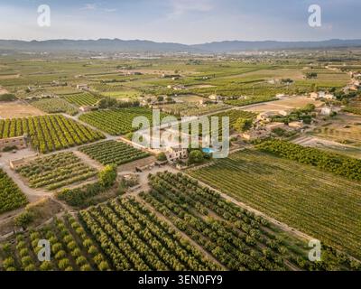 Aus der Vogelperspektive auf eine weite Landschaft mit Farmen und Feldern, die sich bis zu entfernten Bergen erstrecken. Stockfoto