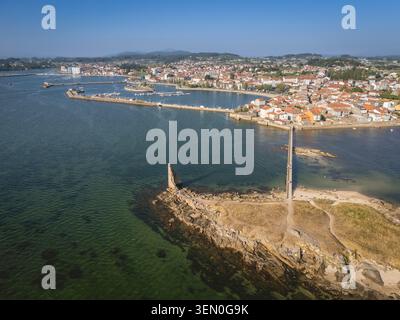 Aus der Vogelperspektive auf eine Küstenstadt mit einem langen Pier und einem historischen Turm am Meer. Stockfoto