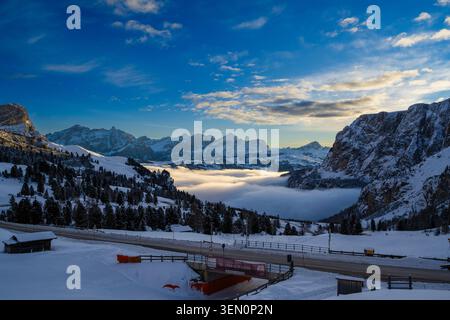 Atemberaubende Winterberglandschaft mit schneebedeckten Gipfeln und einem wolkengefüllten Tal bei Sonnenuntergang. Stockfoto