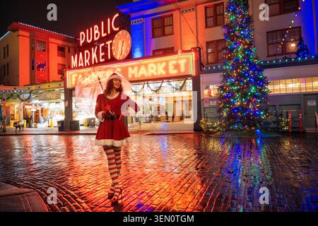 Festliche Urlaubsszene mit einer Frau in Weihnachtskleidung auf einem lebhaften Stadtmarkt bei Nacht. Seattle, USA Stockfoto