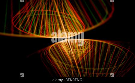 Abstrakte Lichtmuster mit leuchtenden roten und grünen geschwungenen Linien auf schwarzem Hintergrund. Stockfoto