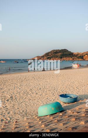 Friedliche Strandszene mit blauen Fischerbooten am Sandstrand und Hügeln im Hintergrund. Stockfoto