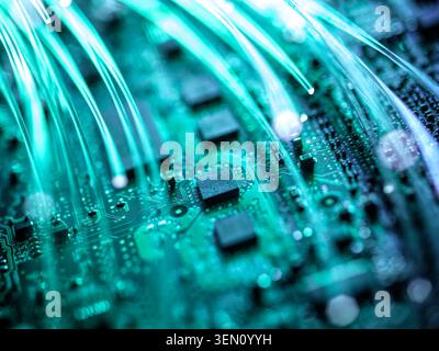 Nahaufnahme einer grünen Leiterplatte mit glühenden Glasfaserlitzen. Stockfoto