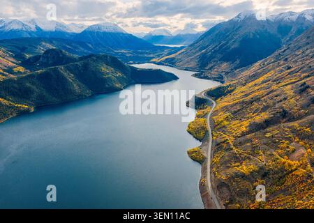 Aus der Vogelperspektive eines sich windenden Flusses durch eine bergige Herbstlandschaft mit gelbem Laub. Stockfoto