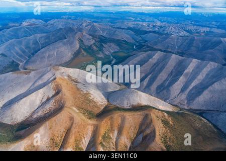 Panoramablick auf weitläufige, mehrschichtige Bergketten unter bewölktem Himmel mit sichtbaren grünen Tälern. Stockfoto