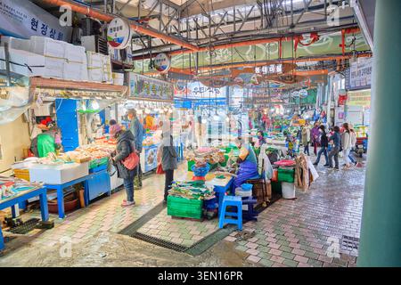 Lebendige, traditionelle Marktszene auf Jeju Island mit frischen Meeresprodukten und geschäftigen Einkäufern an lebhaften Ständen für Meeresfrüchte. Stockfoto