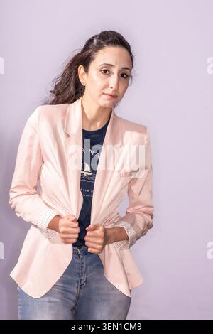 Nayrouz Qarmout steht gerade und zeigt einen selbstbewussten Ausdruck. Sie trägt einen leichten Blazer über einem T-Shirt und hat ihre Hände vor sich. Stockfoto