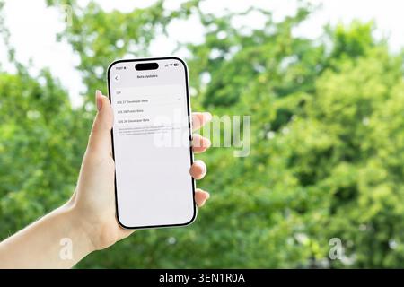 Posen, Polen – 9. Juni 2026: Person, die ein Smartphone mit iOS 27-EntwicklerBeta-Einstellungen auf einem Bildschirm hält, die moderne mobile Betriebssysteme veranschaulichen Stockfoto