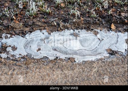 Eine kleine eisige Pfütze auf einer Feldstraße an einem kalten Wintertag Stockfoto