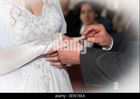 Braut und Bräutigam tauschen Eheringe aus, Bräutigam legt den Ehering an den Finger seiner Frau Stockfoto