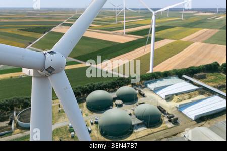 Synergie mit grüner Energie. Nahaufnahme der Windkraftanlage mit Infrastruktur der Biogasanlage im Hintergrund Stockfoto