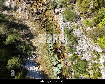 Luftbild von klarem türkisfarbenem Wasser, Steinen und Wald entlang eines alpinen Baches im Triglav-Nationalpark, Slowenien. Stockfoto