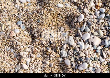 Nahaufnahme von Meersand und bunten Kieselsteinen am Strand. Stockfoto