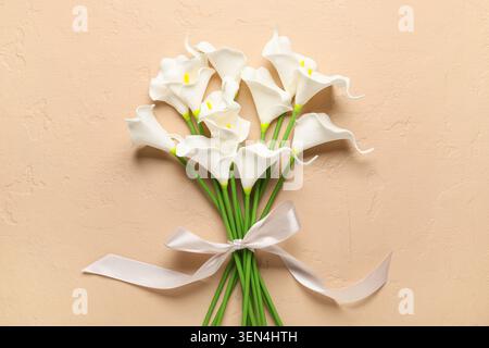 Künstliche Calla-Lilienblüten auf beigefarbenem Hintergrund Stockfoto