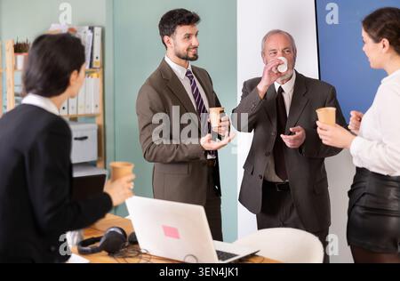 Kaffeepause – Gruppe von Büroangestellten trinkt Kaffee und plaudert während der Pause miteinander Stockfoto
