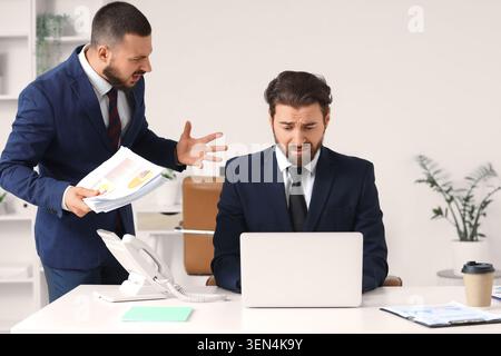 Wütender Boss, der gestresste Mitarbeiter im Büro anschreit, Konflikte am Arbeitsplatz und geschäftlicher Druck Stockfoto