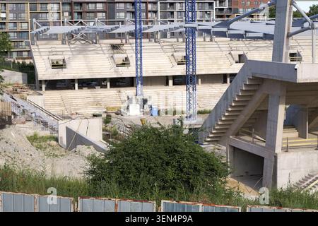 Neues Stadionbetongebäude in einem laufenden Stadtentwicklungsprojekt mit Sitzreihen, Treppen und Kränen, die Wachstum symbolisieren, Investition, A Stockfoto