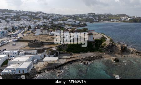 Drohnenblick auf die berühmten Windmühlen von Mykonos neben Little Venice, weiße Häuser, felsige Küste und Ägäis. Stockfoto