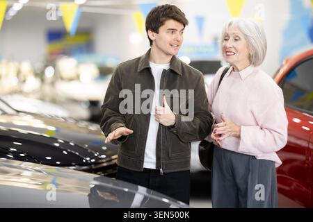 Der erwachsene Sohn hilft ihrer älteren Mutter bei der Wahl eines neuen Autos im Autohaus Stockfoto