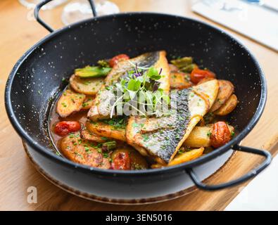 Seebrassen-Filets mit gerösteten Kartoffeln und Kirschtomaten in einer Pfanne Stockfoto