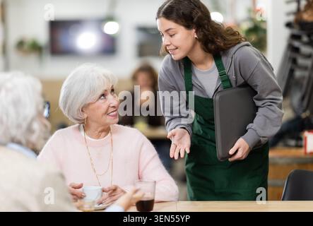 Eine Kellnerin nimmt eine Bestellung von älteren Frauen in einem Café entgegen Stockfoto