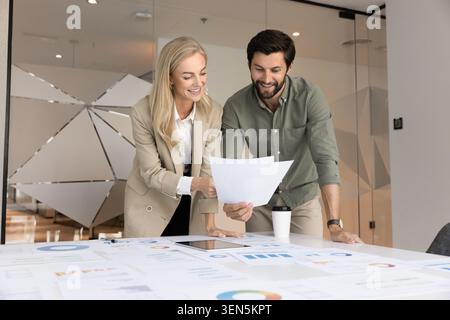 Lächelnde Kollegen, die im Amt Finanzberichte prüfen Stockfoto