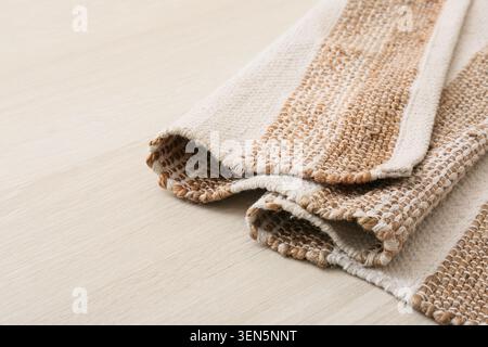 Gefaltetes Naturfaser-Gewebe auf heller Holzoberfläche, Bio-Wohnkultur und nachhaltiges Wohnen Stockfoto