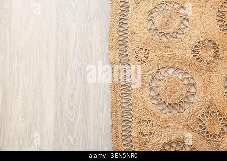 Geflochtener Teppich aus natürlichem Jute mit kreisförmigen Mustern auf hellem Holzboden, nachhaltiger Wohnkultur und Inneneinrichtung, die gewebte Textur des Teppichs bietet Stockfoto