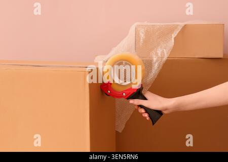 Hand mit Bandspender zum Verschließen von Kartons für Transport oder Versand, Verpackung und Logistik Stockfoto
