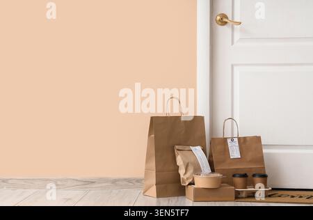 Kontaktloser Essenslieferservice mit braunen Papiertüten und Kaffeetassen vor der Tür, Hausessen zum Mitnehmen Stockfoto