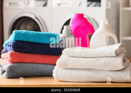 Frisch gewaschene Wäsche mit gestapelten Handtüchern und Waschmittelflaschen in einem modernen Waschraum, Stapel bunter Handtücher, inklusive Stockfoto