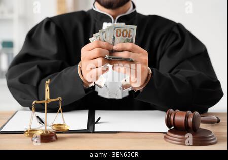 Korrupter Richter in Handschellen hält Bestechungsgeld, Integrität des Justizsystems und rechtliche Ethik-Verletzung Konzept, ein Richter in Handschellen hält einen Stapel Hun Stockfoto
