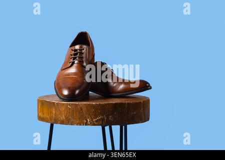 Elegante braune oxford-Lederschuhe für Herren auf Holzhocker, modische Schuhe für geschäftliche und formelle Anlässe Stockfoto