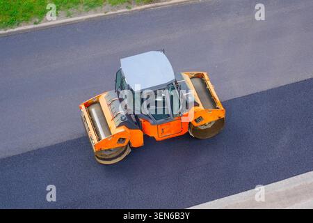 Straßenreparatur-Straßenrollenmaschine rollt Asphalt Stadtstraße, Luftsicht. Stockfoto