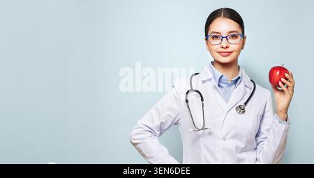 Porträt einer jungen Ärztin im Labormantel mit grünem Apfel. Ernährung und gesunde Ernährung Stockfoto