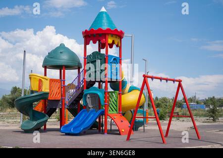 Farbenfroher Kinderspielplatz mit Rutschen, Klettergerüsten und Spielgeräten in einem Outdoor Park an einem sonnigen Tag unter blauem Himmel mit Wolken. Stockfoto