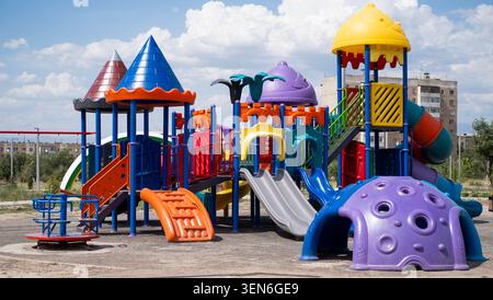 Farbenfroher Kinderspielplatz mit Rutschen, Klettergerüsten und Spielgeräten in einem Outdoor Park an einem sonnigen Tag unter blauem Himmel mit Wolken. Stockfoto