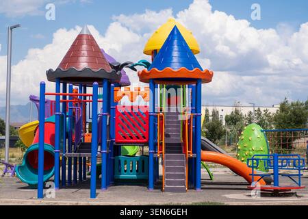 Farbenfroher Kinderspielplatz mit Rutschen, Klettergerüsten und Spielgeräten in einem Outdoor Park an einem sonnigen Tag unter blauem Himmel mit Wolken. Stockfoto