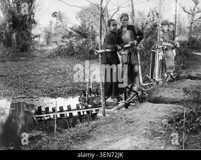 Ein einfaches, fußbetriebenes Becherwerk bewässert landwirtschaftliche Flächen in Tonkin, Vietnam, auf einem monochromen Foto des frühen 20. Jahrhunderts. Das Bild zeigt ein traditionelles Wasserhebegerät, das für Bewässerung und ländliche Landwirtschaft in der Region verwendet wird. Stockfoto