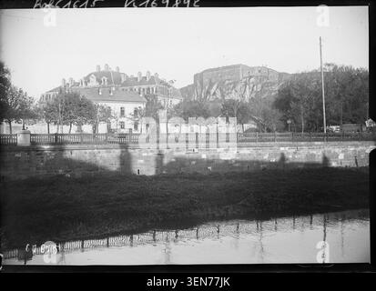 Belfort Castle und der Löwe von Belfort erheben sich auf diesem Pressefoto von 1920 über den Savoureuse River. Die Aussicht verbindet die Festung, Bartholdis monumentale Löwenskulptur und die umliegende Landschaft von Belfort. Stockfoto