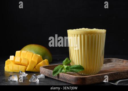 Kurkuma-Lassie oder Mangolassi auf schwarzem Hintergrund mit Kopierraum. Traditionelles indisches kaltes Getränk mit Mango. Frische Lassi aus Joghurt, Wasser, Gewürzen, Obst und Eis. Stockfoto