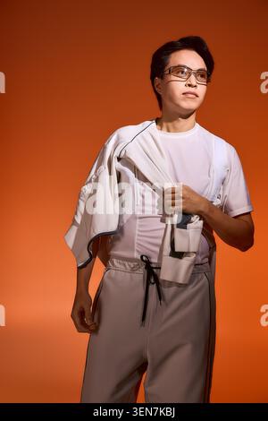 Ein selbstbewusster junger asiatischer Mann zeigt sein modisches Outfit in einer farbenfrohen Studiokulisse. Stockfoto