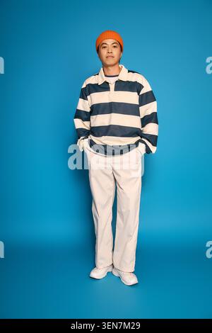 Ein junger asiatischer Mann zeigt seinen einzigartigen Stil und sein Selbstvertrauen in einem hellen Studio. Stockfoto