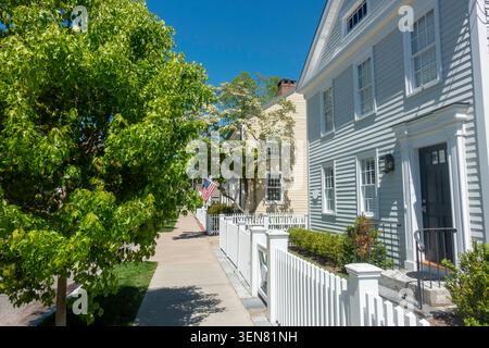 Eine Reihe von Häusern auf einem von Bäumen gesäumten Bürgersteig an der Main Street in der New England Stadt Essex, CT im Frühjahr Stockfoto