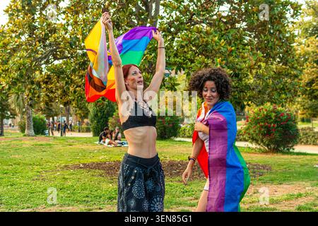 Frauen feiern Vielfalt und Stolz mit Regenbogenflaggen im Park Stockfoto