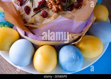 Osterkomposition. Dekorierter süßer Osterkuchen, bemalt Eier auf einem Teller. Platz für Text. Osterkuchen und bemalte Eier. Stockfoto