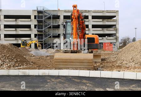 Bagger im Einsatz auf dem Land außerhalb eines modernen Industriebetriebes im Bau. Vorderansicht. Stockfoto