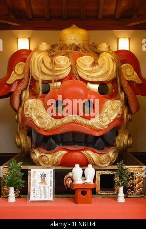 Eine riesige dekorative, rot-goldene Shishi-Löwen-Schutzmaske in einem Shinto-Schrein-Gebäude in Tokio, Japan Stockfoto