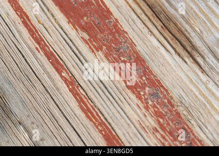 Nahaufnahme einer alten Holzoberfläche mit abblätternder roter Farbe und rostiger Schraube, die rustikale Textur, Vintage-Design und Verfall natürlicher Materialien symbolisiert Stockfoto