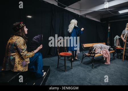 Junge Schauspieler, die eine Theaterszene auf einer kleinen Bühne mit Bank und Requisiten Proben Stockfoto